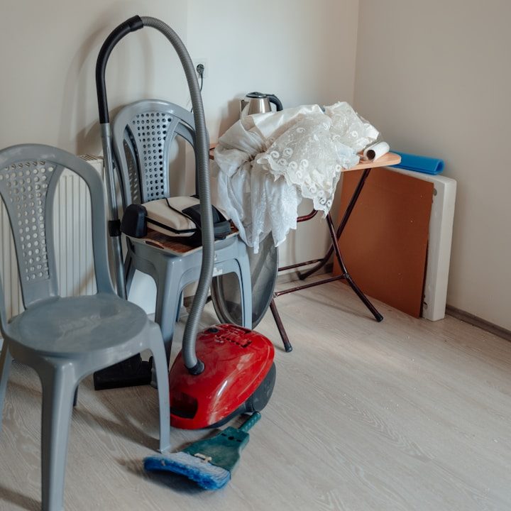 Ein Raum mit zwei Stühlen, einem Staubsauger und verschiedenen Gegenständen auf einem Tisch.