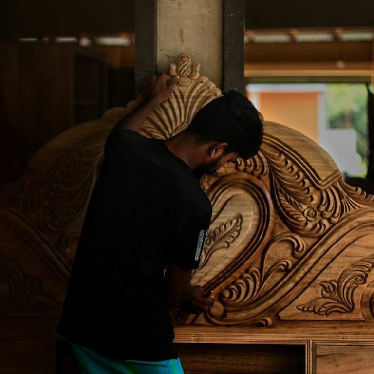 Ein Handwerker schnitzt kunstvolle Holzverzierungen an einem Möbelstück.
