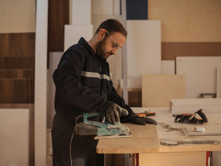 Handwerker, der an einem Tisch mit Werkzeugen arbeitet. Holz und Materialien um ihn herum.